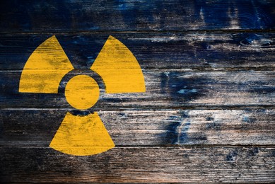 Image of Radioactive sign on wooden background, space for text. Hazard symbol