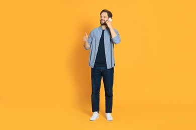 Photo of Man talking on smartphone against orange background