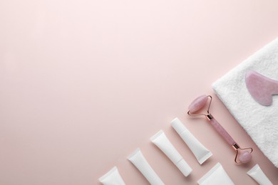 Photo of Natural face roller, gua sha tool, cosmetic products and towel on pink background, flat lay. Space for text