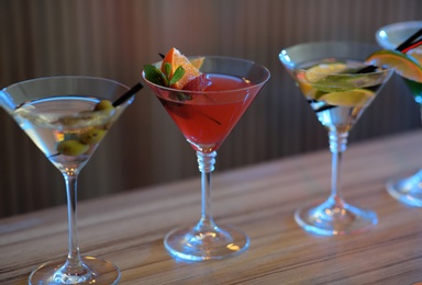 Photo of Different martini cocktails on table in bar, closeup