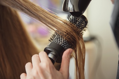 Photo of Professional hairdresser working with client in salon