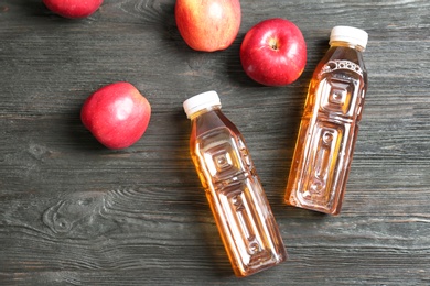 Bottles of apple juice on dark wooden background, top view