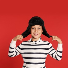 Photo of Cute little boy in hat and sweater on red background. Winter season