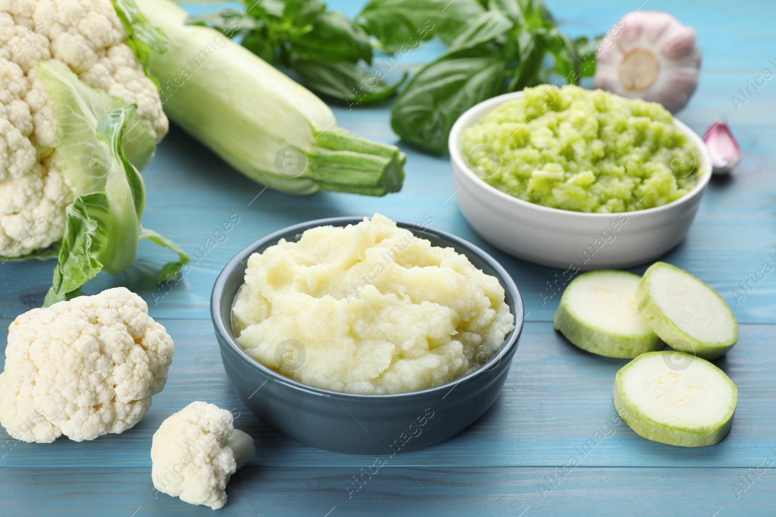 Photo of Tasty puree in bowls and ingredients on light blue wooden table