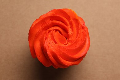 Photo of Delicious cupcake with bright cream on brown background, top view