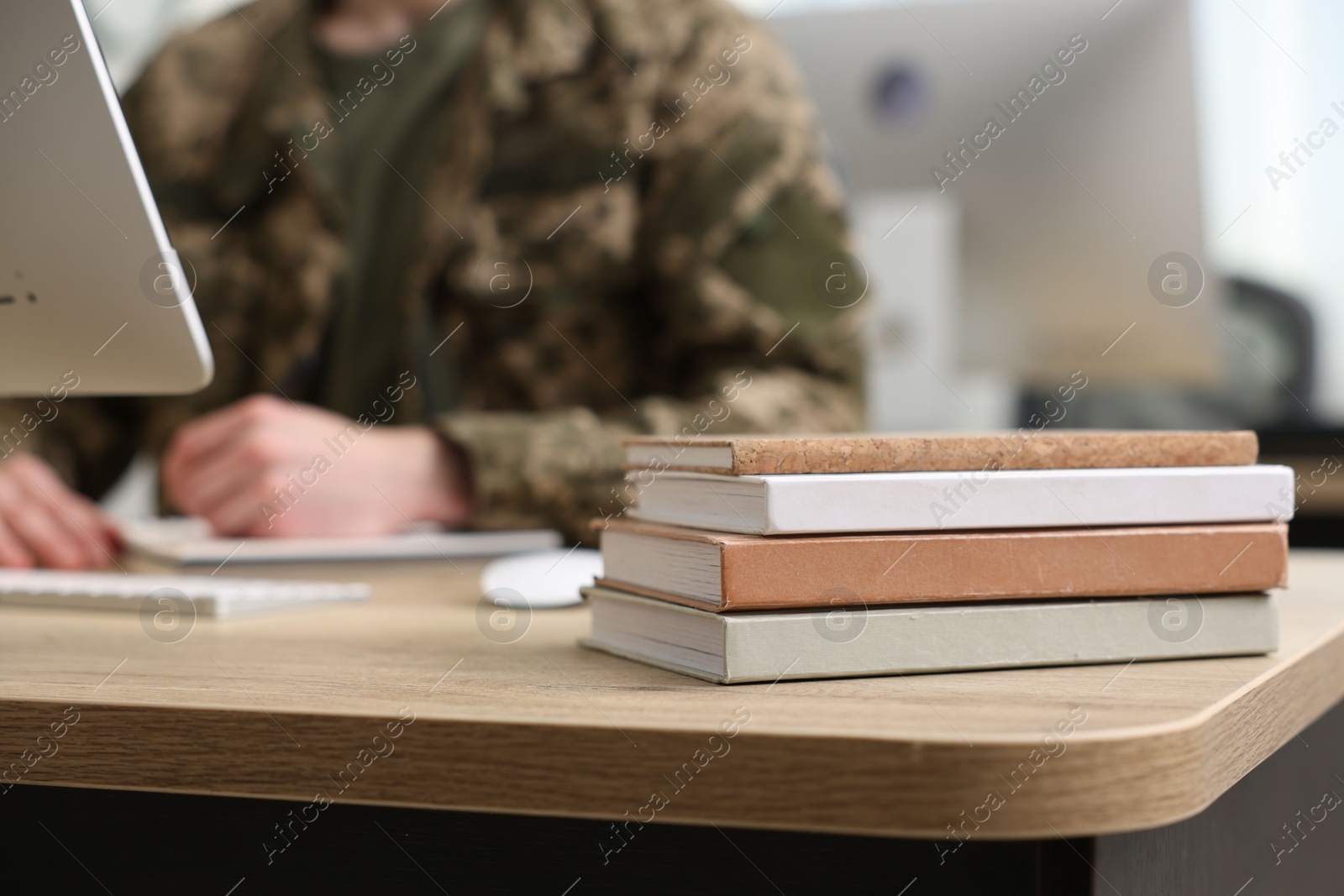 Photo of Military education. Student in soldier uniform learning at wooden table indoors, selective focus