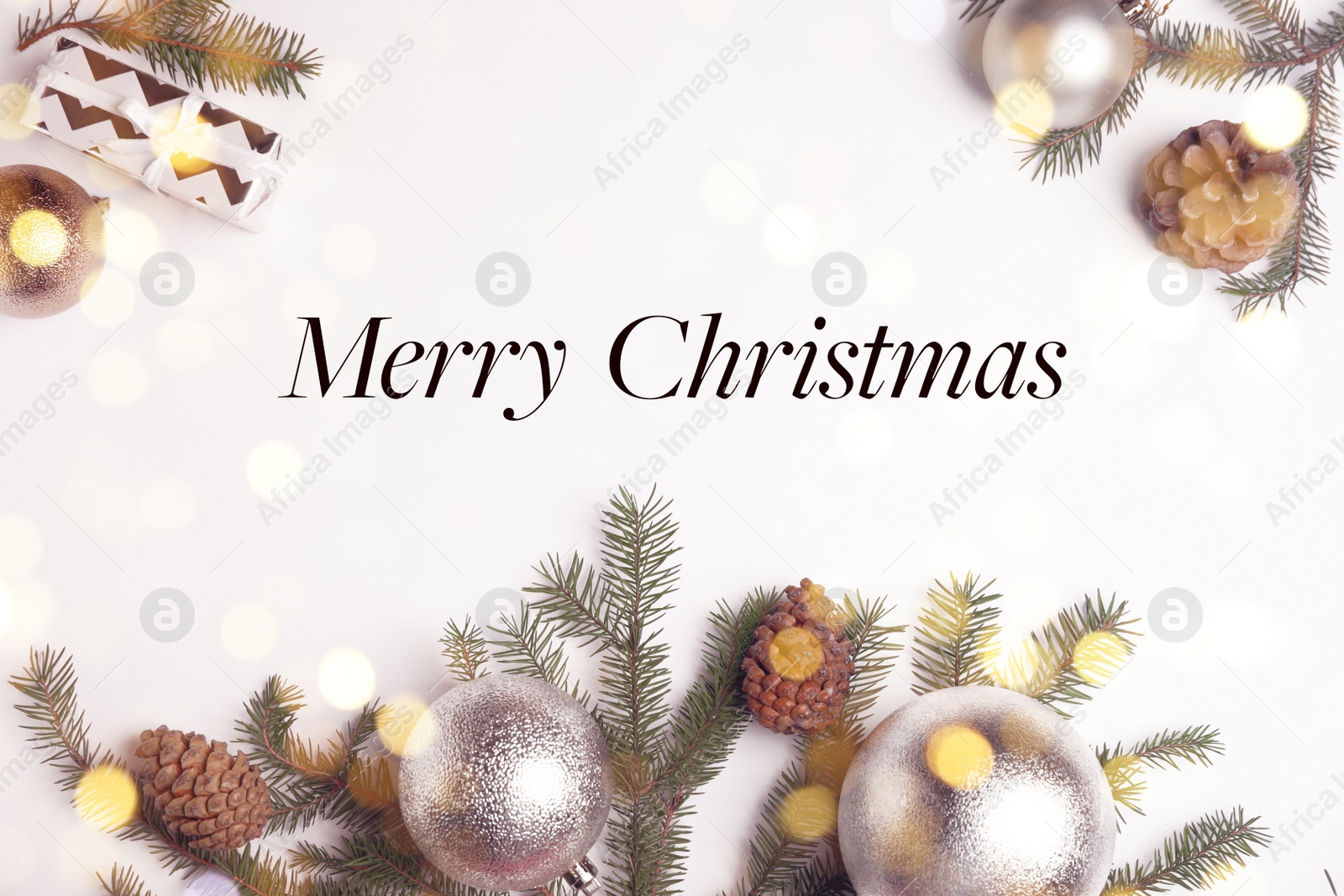 Image of Greeting card with phrase Merry Christmas. Beautiful fir tree branches and festive decor on white wooden table, flat lay. Bokeh effect