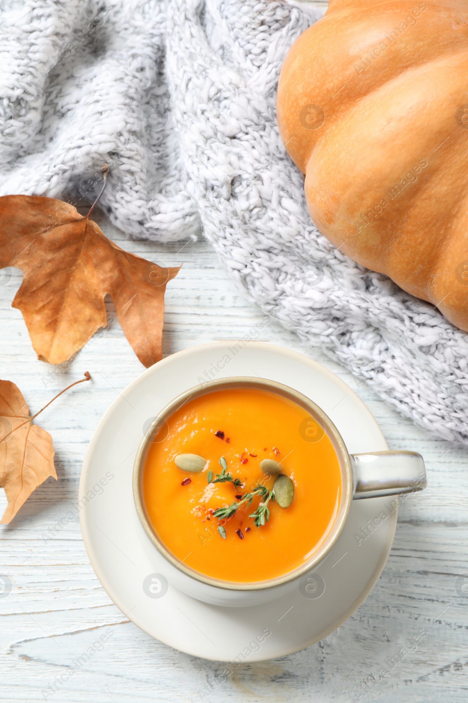 Photo of Delicious pumpkin soup in cup on white wooden table, flat lay