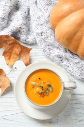 Photo of Delicious pumpkin soup in cup on white wooden table, flat lay