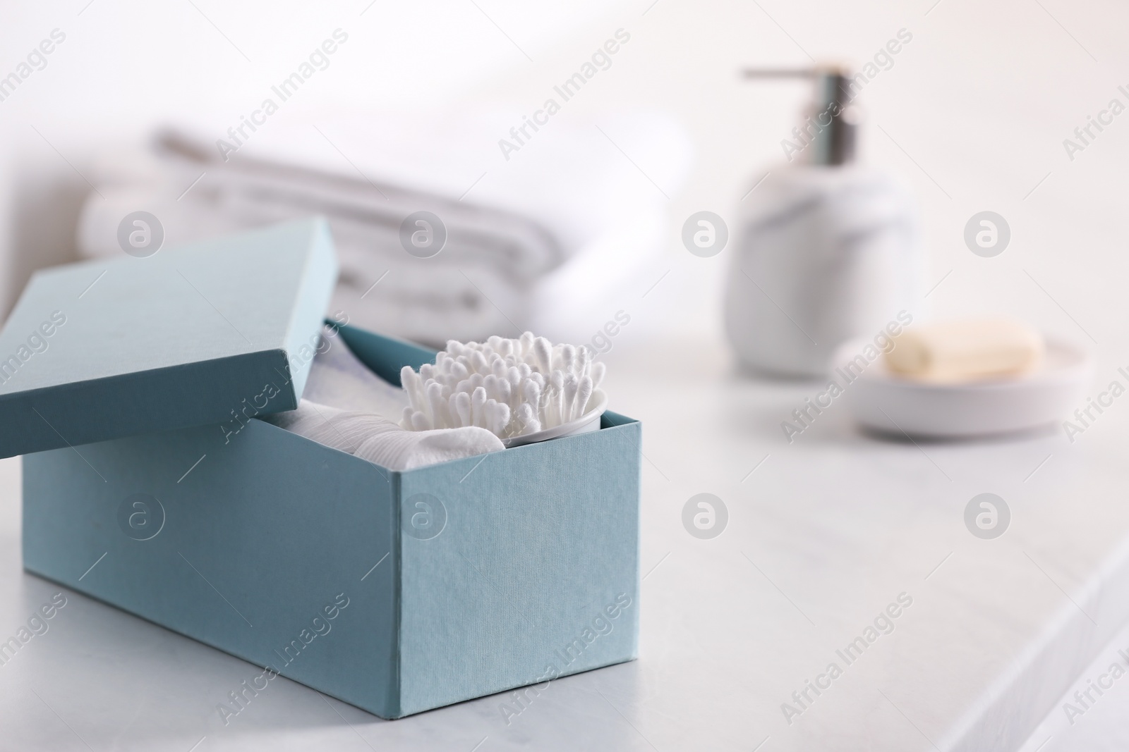 Photo of Cotton buds and pads in box on white table indoors