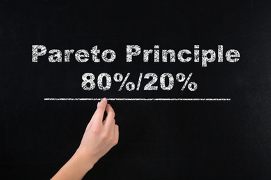 Pareto principle concept. Woman writing 80%/20% on chalkboard, closeup