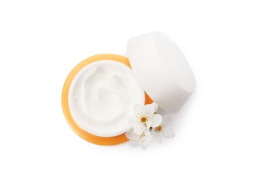 Face cream in jar and flowers on white background, top view