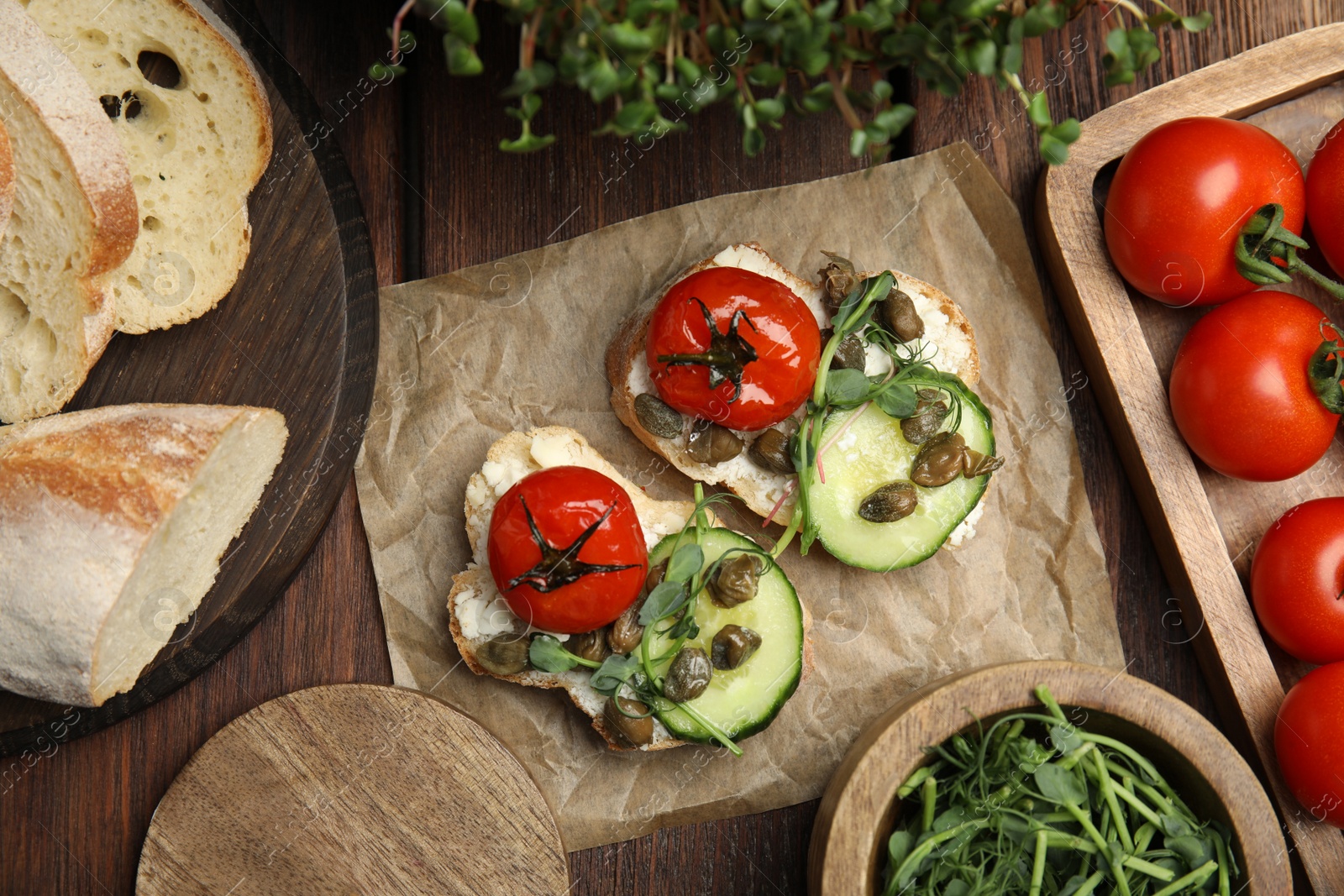 Photo of Tasty bruschettas with vegetables and capers served on wooden table, flat lay