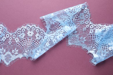 Photo of White lace on purple background, top view