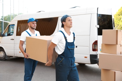 Male movers unloading boxes from van outdoors