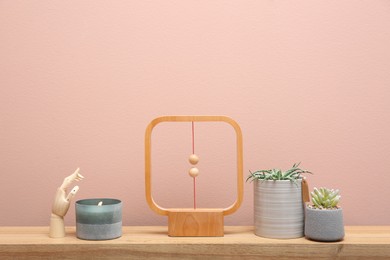 Photo of Beautiful potted plants and different accessories on wooden table near pink wall. Interior design