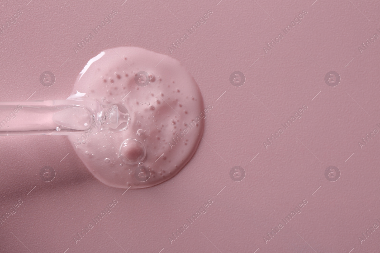 Photo of Pipette with cosmetic serum on pink background, top view. Space for text