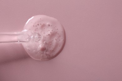 Photo of Pipette with cosmetic serum on pink background, top view. Space for text