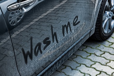 Photo of Phrase Wash Me written on dirty car, closeup