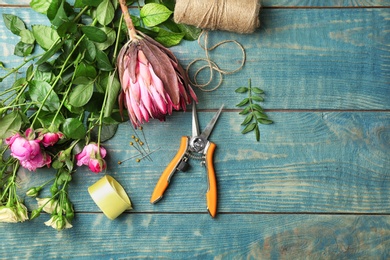 Florist equipment with flowers on wooden background, top view
