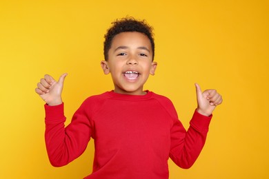 Photo of African-American boy showing thumbs up on yellow background