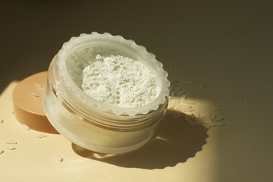 Photo of Rice loose face powder on beige background, closeup. Space for text