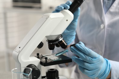 Photo of Scientist working with microscope in laboratory, closeup