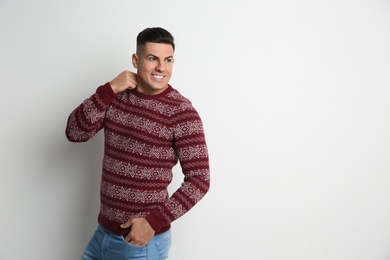 Photo of Handsome man in Christmas sweater on white background, space for text