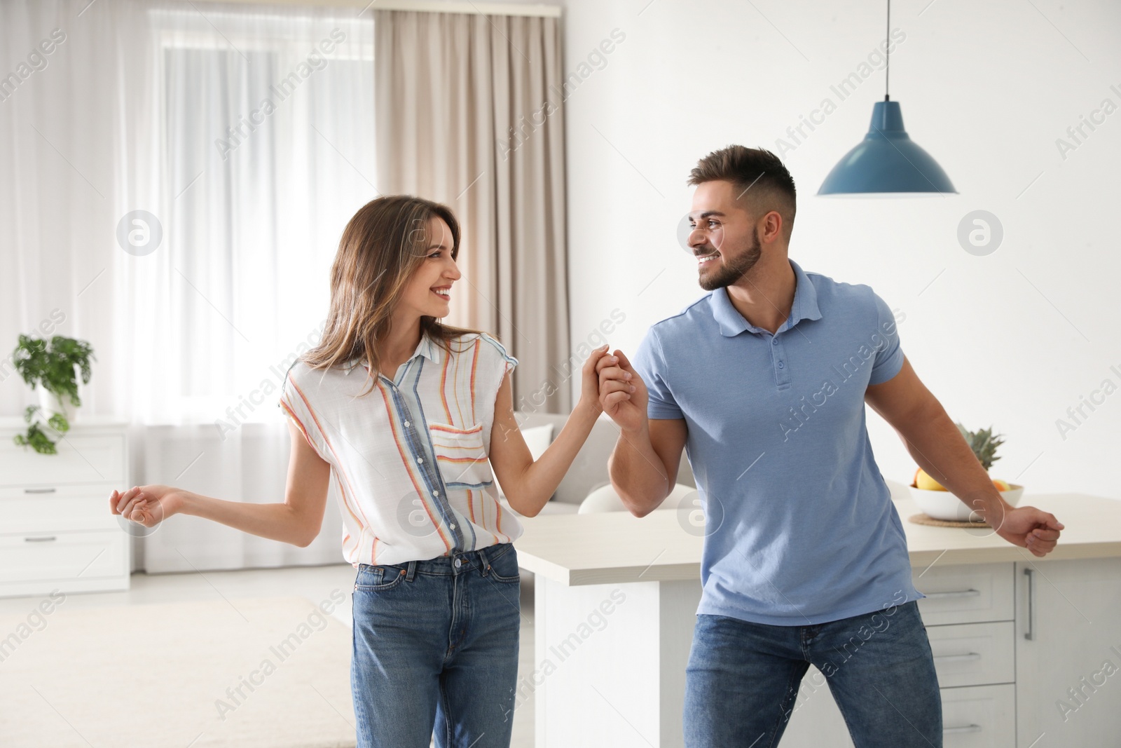 Photo of Lovely young couple dancing in kitchen at home