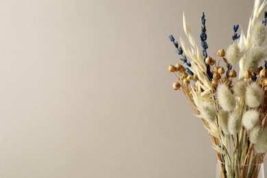 Dried flowers in vase against light background. Space for text
