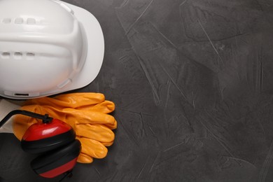 Photo of Hard hat, gloves and earmuffs on grey table, flat lay with space for text. Safety equipment