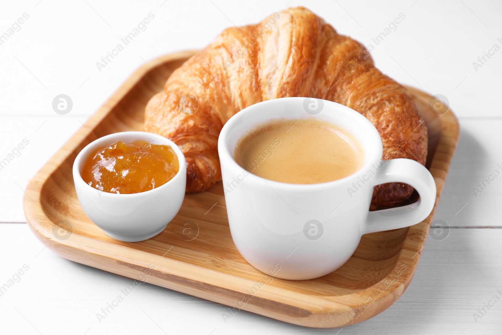 Photo of Fresh croissant, jam and coffee on white wooden table, closeup. Tasty breakfast