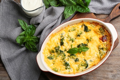 Photo of Flat lay composition with tasty broccoli casserole on wooden table