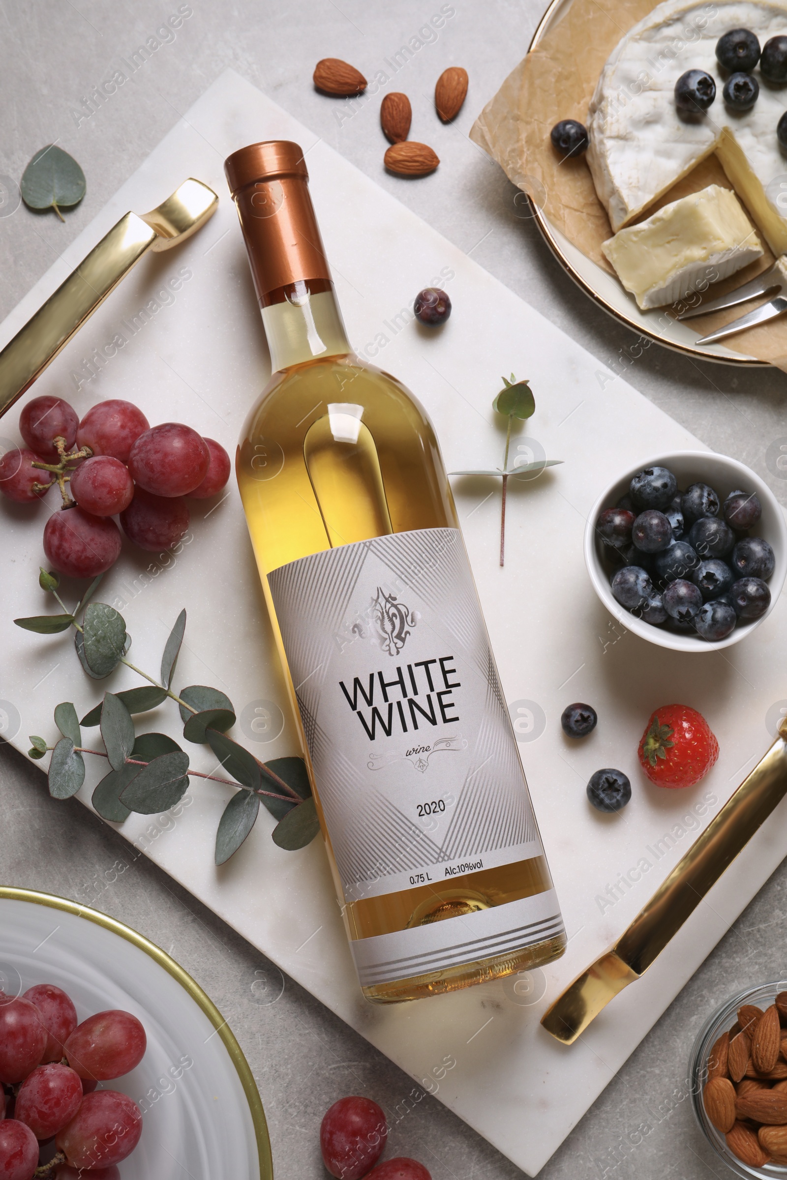 Photo of Flat lay composition with bottle of white wine and snacks on grey table