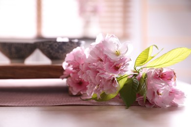 Photo of Sakura flowers near cups on table. Traditional tea ceremony