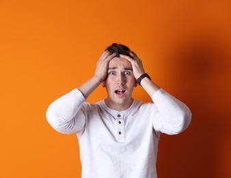 Handsome emotional young man on color background