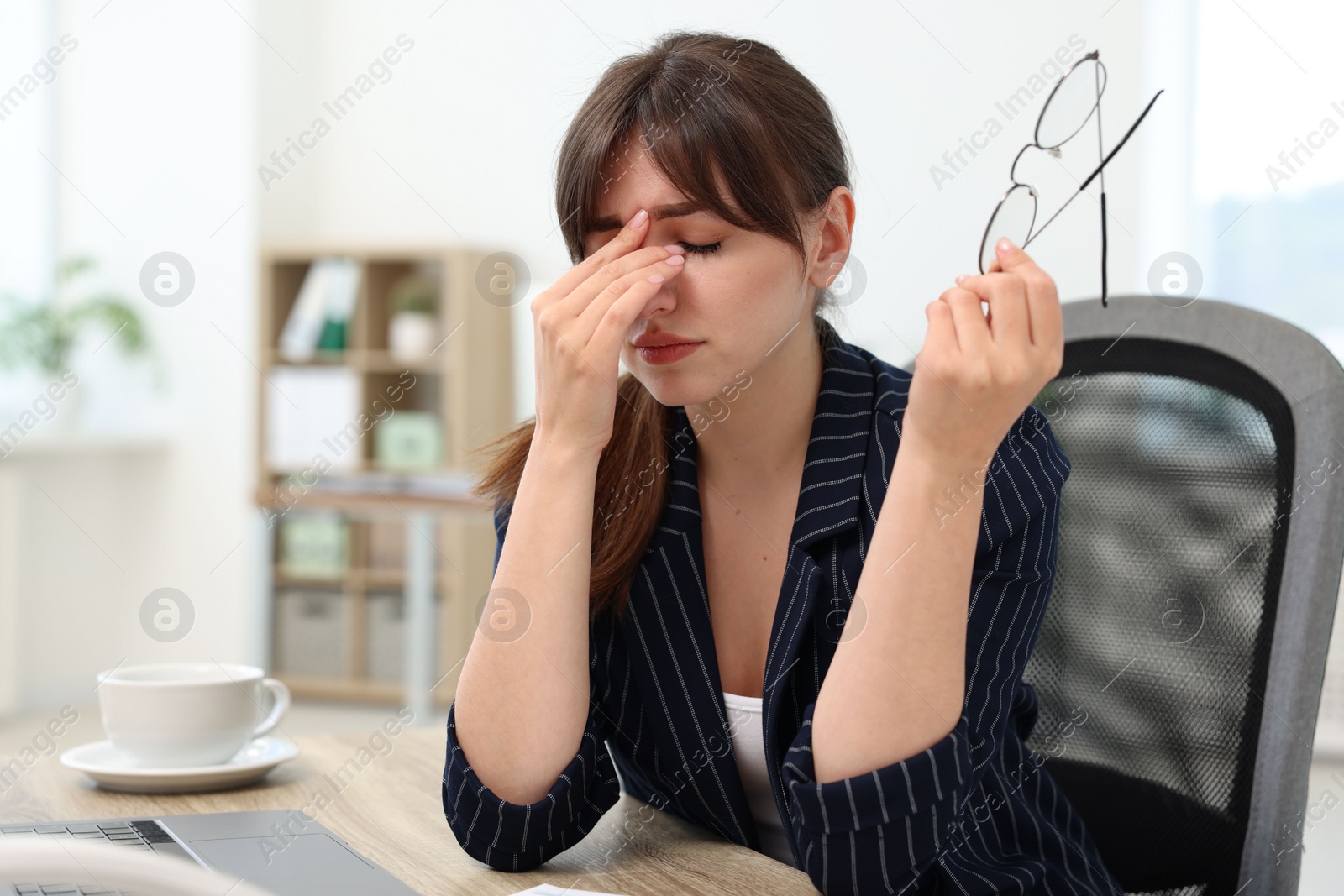 Photo of Overwhelmed woman with glasses suffering at table in office