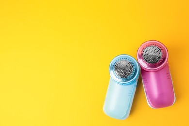 Photo of Modern fabric shavers on yellow background, flat lay. Space for text