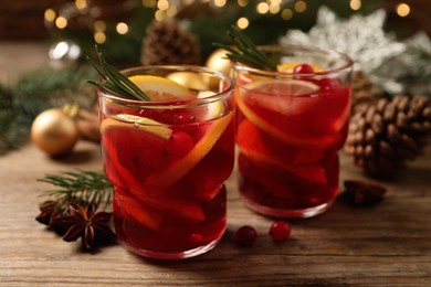 Delicious punch drink with cranberries and orange on wooden table against blurred festive lights