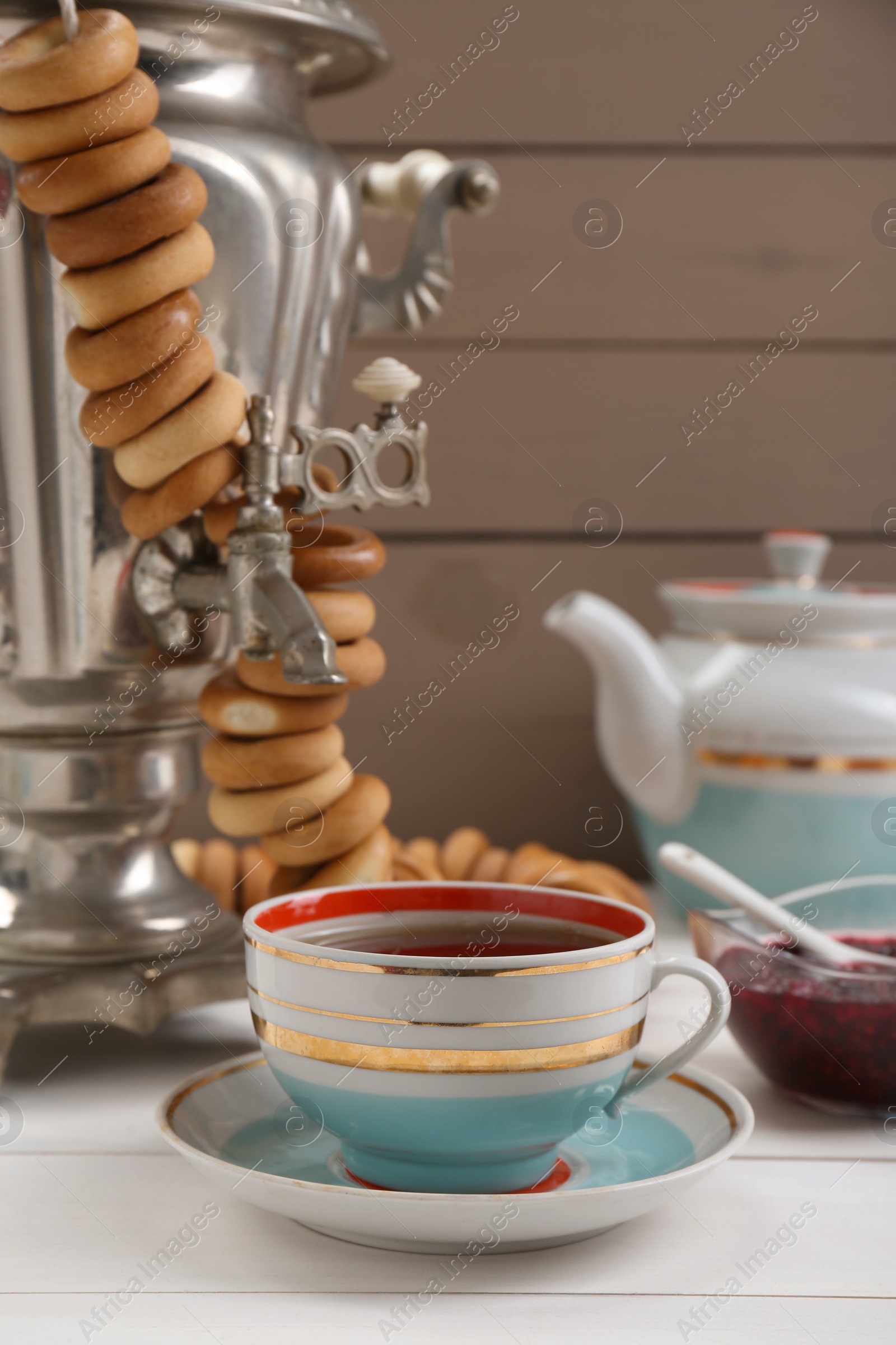 Photo of Cup of tea and delicious ring shaped Sushki (dry bagels) on white wooden table