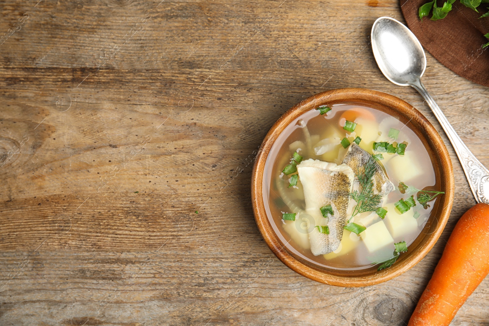 Photo of Delicious fish soup served on wooden table, flat lay. Space for text