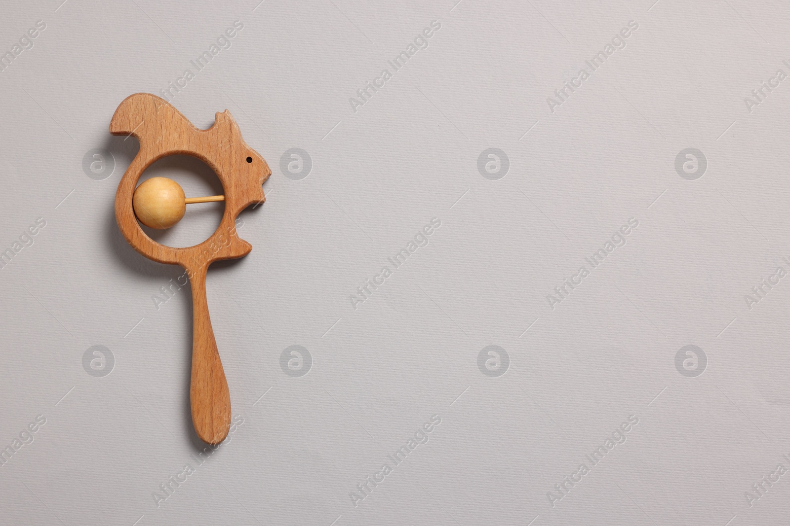 Photo of Baby accessory. Wooden rattle on grey background, top view. Space for text