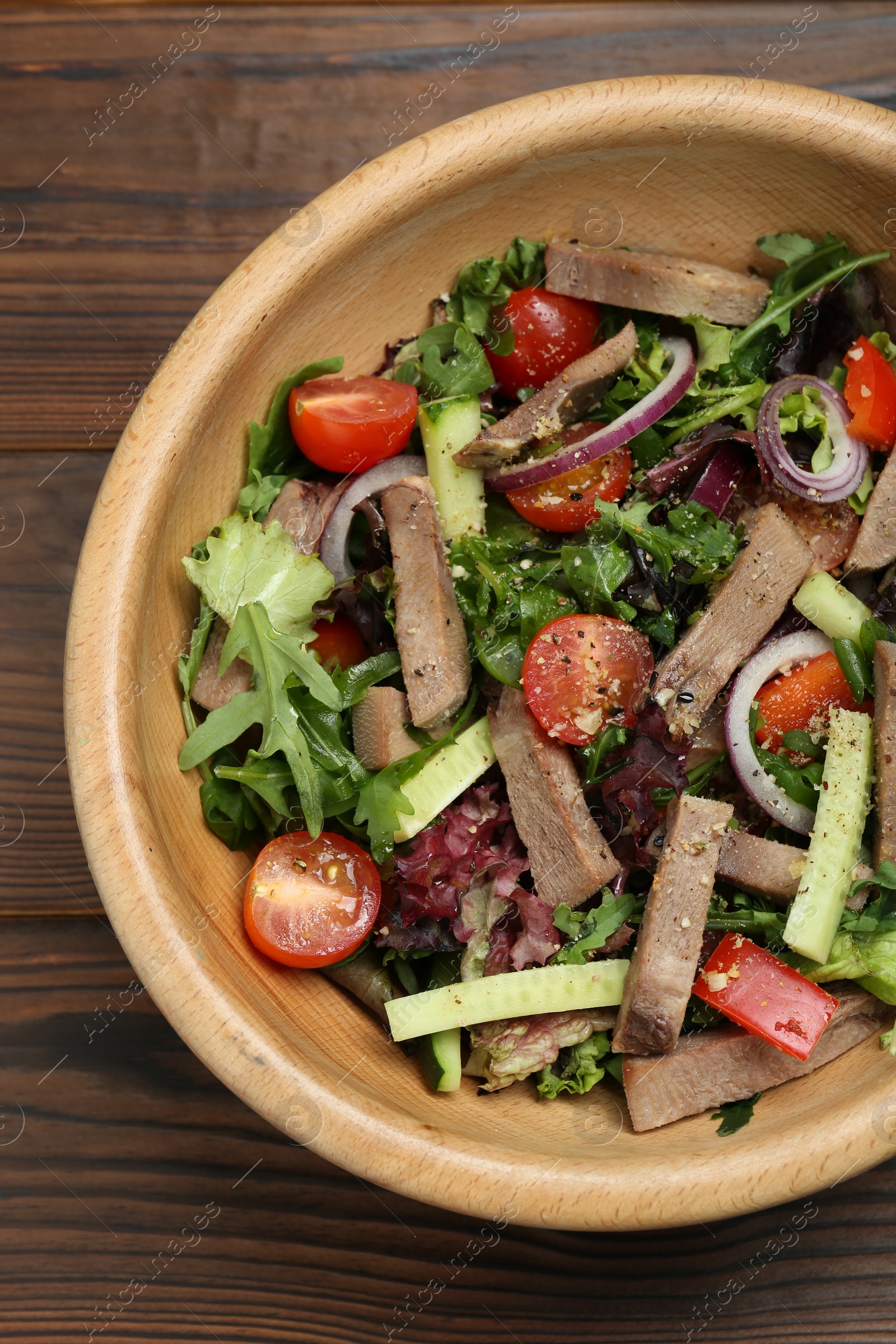 Photo of Delicious salad with beef tongue and vegetables on wooden table, top view