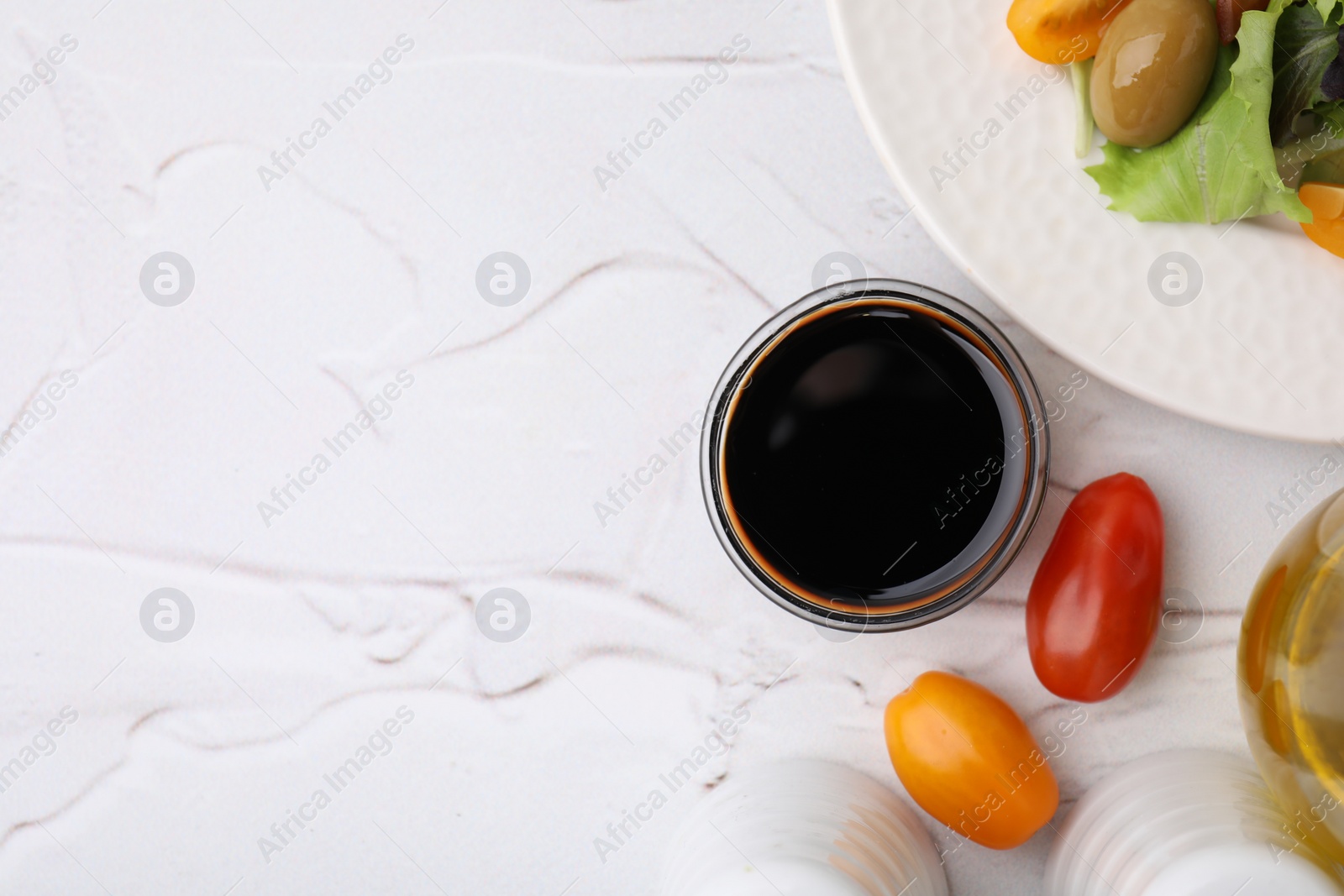 Photo of Tasty vinegar in bowl, tomatoes and salad on light textured table, flat lay. Space for text