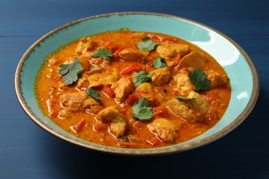 Photo of Delicious chicken curry on blue wooden table, closeup