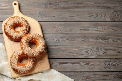 Photo of Delicious fresh bagels with sesame seeds on wooden table, top view. Space for text