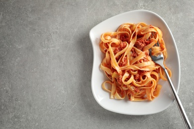 Photo of Plate with delicious pasta bolognese on grey background, top view