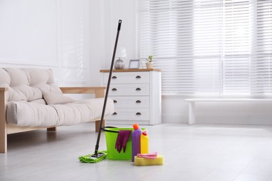 Photo of Mop and cleaning supplies on floor in room