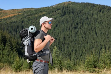 Photo of Man with backpack and sleeping mat in mountains. Space for text