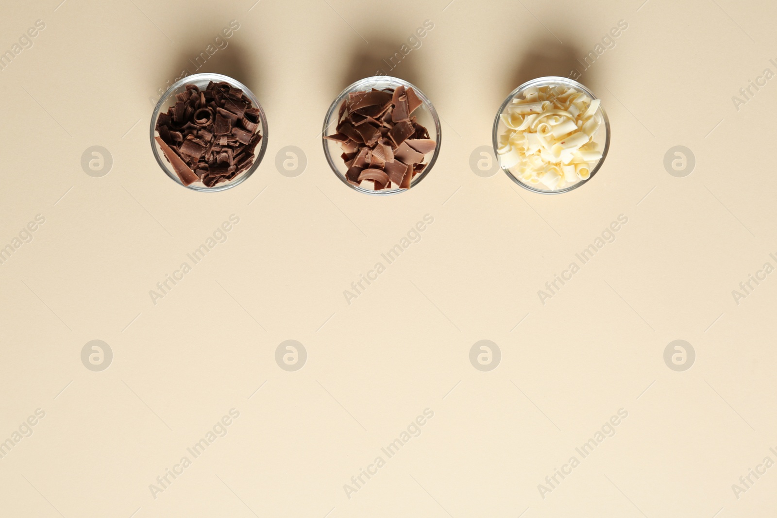 Photo of Bowls with different chocolate curls and space for text on color background, top view